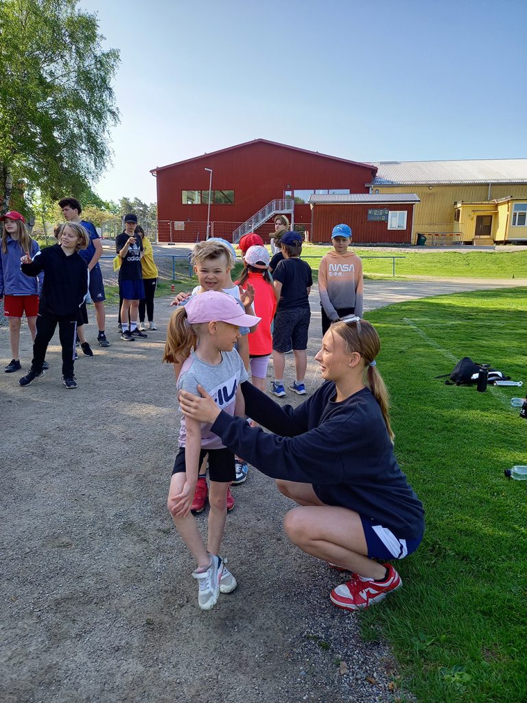 En vuxen som sitter på huk framför ett barn och de pratar med varandra.