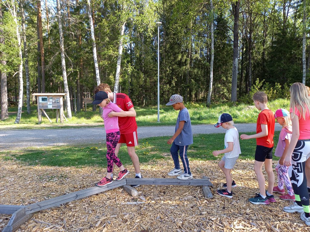 Barn som går balansgång på en planka på en hinderbana.